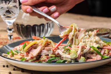 Jambon, soğan, salatalık ve salata soslu taze salata ile kadın eli. 