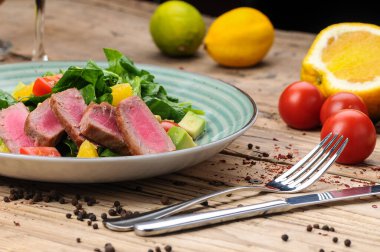 Avokado salatası, çatal, bıçak ve domatesli ton balığı.