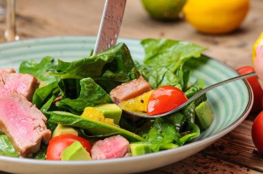 Avokado salatalı ton balığı ve çatallı ve bıçaklı domates.