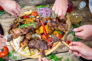 Kızarmış etli kebap, sebzeli ve içkili eller.
