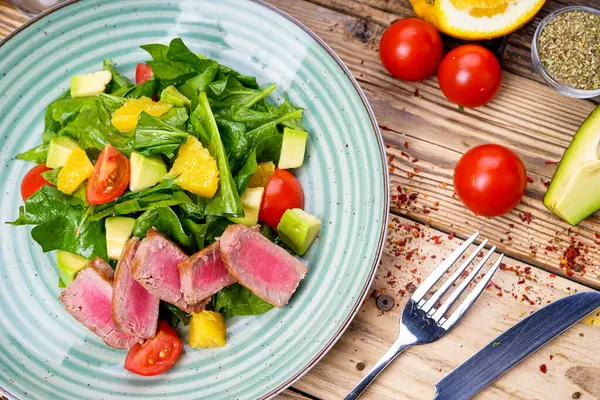 Avokado salatası, çatal, bıçak ve domatesli ton balığı.