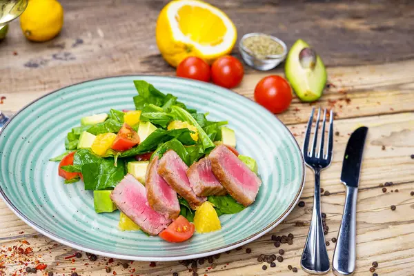 Avokado salatası, çatal, bıçak ve domatesli ton balığı.