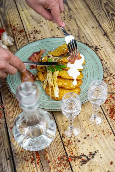 Kızarmış pastırmalı erkek elleri, patatesli mantarlar ve votka.