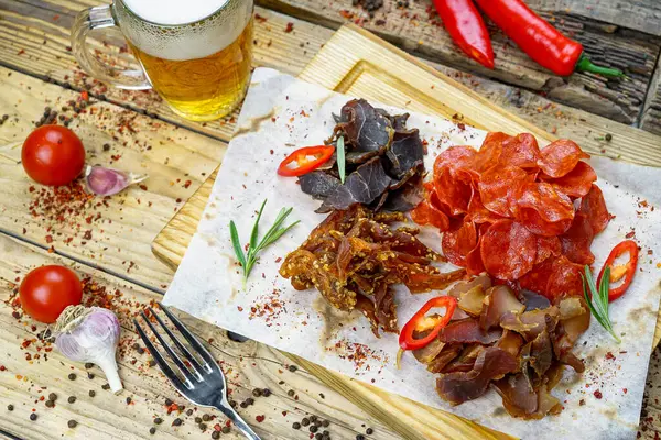 Tuzlanmış et türünde bira aperatifi ve bir bardak bira. 