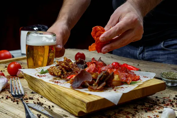 Adam ve tuzlanmış et çeşidi bira aperatifi ve bir bardak bira. 