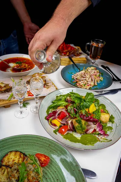 Ukrayna çorbası, salata, ızgara patlıcan ve votka olan insanlar.