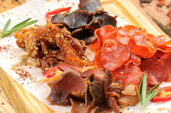 Ahşap masada tuzlanmış et türündeki bira aperatifleri..