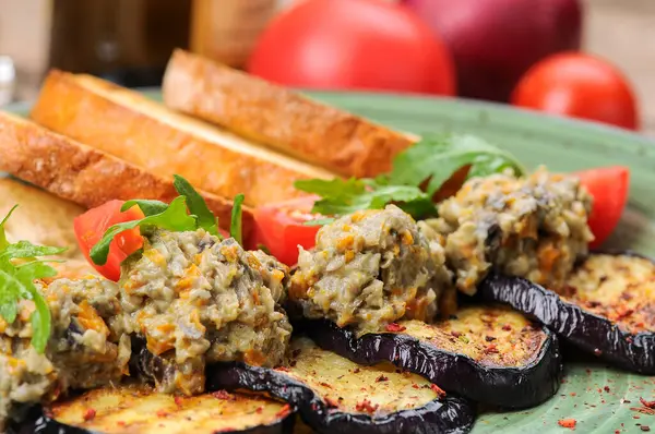 Arka planda domatesli ızgara patlıcan ve ekmek.