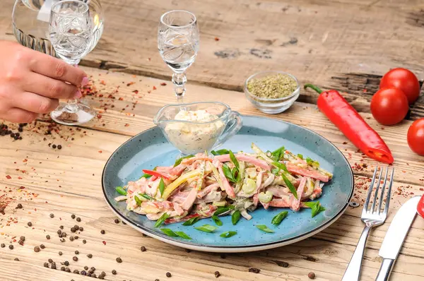 Jambon, soğan, salatalık ve salata soslu taze salata ile kadın eli. 