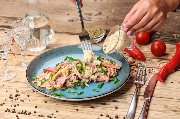 Jambon, soğan, salatalık ve salata soslu taze salata ile kadın elleri. 