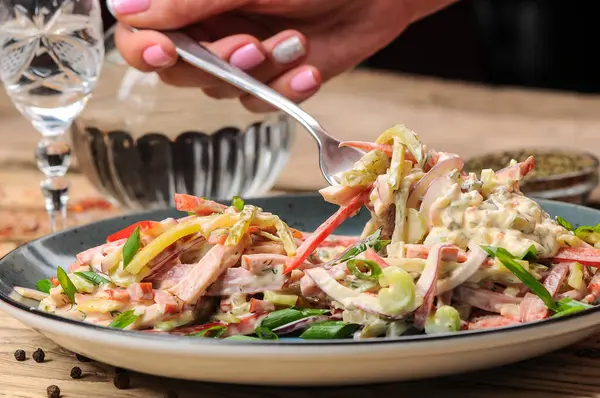 Jambon, soğan, salatalık ve salata soslu taze salata ile kadın eli. 