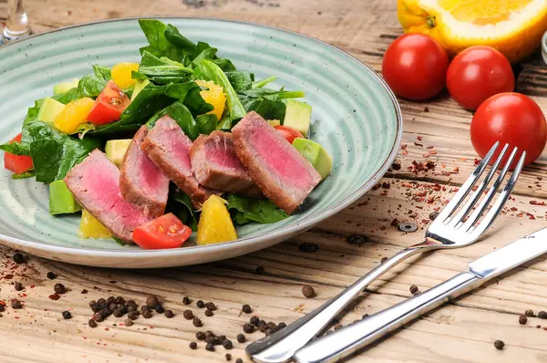 Avokado salatası, çatal, bıçak ve domatesli ton balığı.