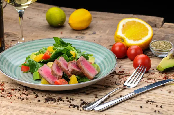 Avokado salatası, çatal, bıçak ve domatesli ton balığı.