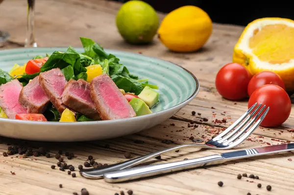 Avokado salatası, çatal, bıçak ve domatesli ton balığı.