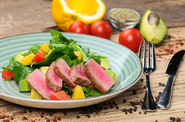 Avokado salatası, çatal, bıçak ve domatesli ton balığı.