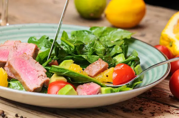 Avokado salatalı ton balığı ve çatallı ve bıçaklı domates.