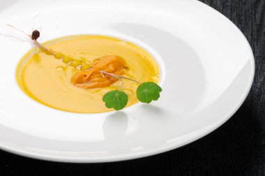 Tabakta yeşil yapraklı lezzetli sarı çorba.