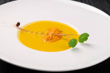 Tabakta yeşil yapraklı lezzetli sarı çorba.