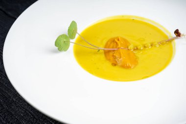 Tabakta yeşil yapraklı lezzetli sarı çorba.