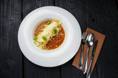 Beyaz tabakta spagetti soslu, çatallı, bıçaklı, kaşıklı.
