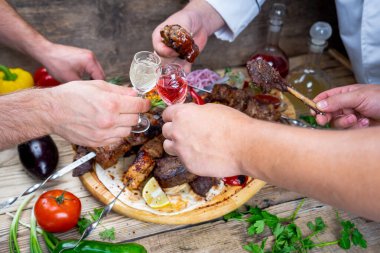 Kızarmış et kebabı, sebze ve alkollü içecekleri olan erkekler.