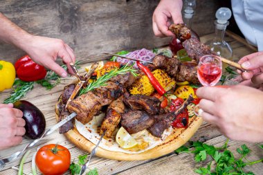 Kızarmış et kebabı, sebze ve alkollü içeceklerle eller.