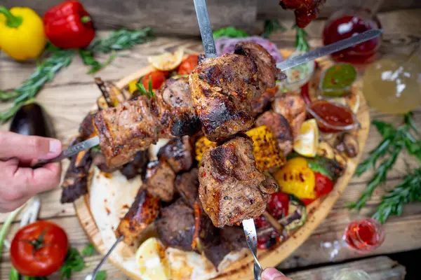 Lezzetli kızarmış et kebabı sebzeli ve taze içecekli eller.