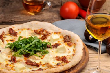 Güneşte kurutulmuş domatesli, peynirli ve yeşillikli pizza manzarası.