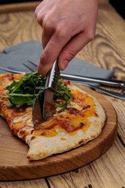 Adam peynirle calzone kesiyor.