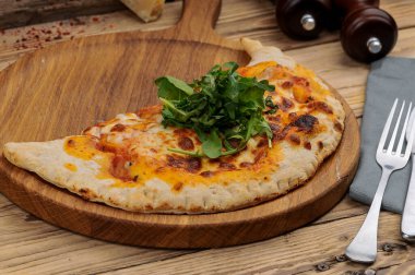 Tahtadaki Calzone pizzasının yakın görüntüsü.