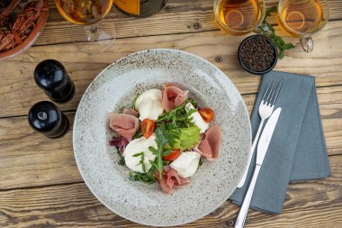 Jambonlu salata, mozzarella, roka ve ahşap arka planda domates.