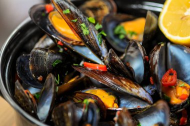 Lezzetli siyah midyeler ve metal kaplar.
