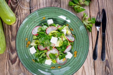 Yeşillik, yumuşak peynir ve ahşap masada dilimlenmiş turplu taze ve lezzetli salata manzarası.