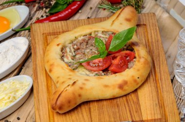 Tahta üzerinde kıyma ve sebzeli Türk pizzası.