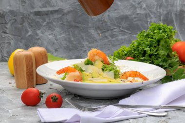 Beyaz tabakta avokado, karides, domates, marul ve parmesan peynirli taze salata