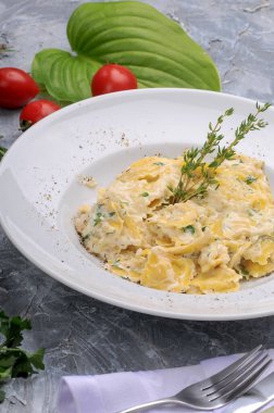 Lezzetli makarna, krem peynir ve beyaz tabakta bitkiler.