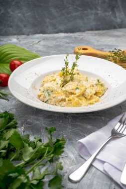 Lezzetli makarna, krem peynir ve beyaz tabakta bitkiler.