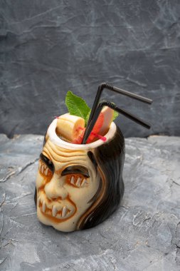 Mermer arka planda pipetle korkunç bir suratı olan bir kokteylin yakın plan fotoğrafı.