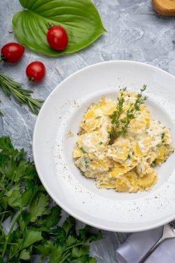 Lezzetli makarna, krem peynir ve beyaz tabakta bitkiler.