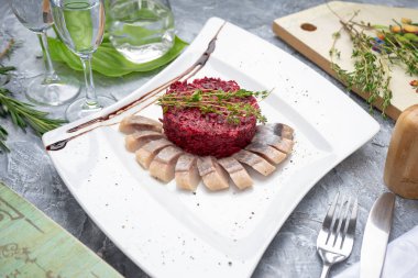 Beyaz tabakta pancar salatası ile lezzetli ringa balığı.