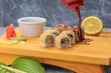 Avokado, salatalık, pirinç ve sosla kaplı sushi ruloları.