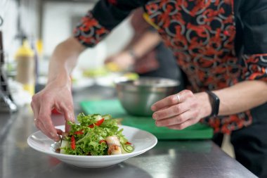 Erkek şef mutfakta taze salata hazırlıyor.