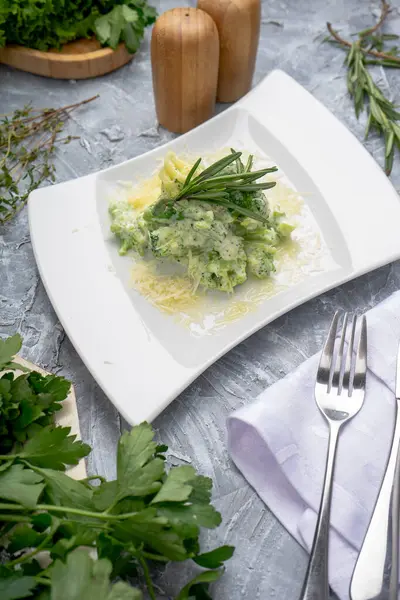 Parmesan peynirli yeşil brokoli ve beyaz tabakta biberiye yaprakları.