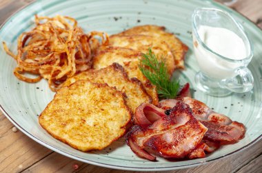 Ekşi krema, dereotu, kızarmış pastırma ve soğanlı patates tabağından Ukrayna ulusal yemeği Deruni.