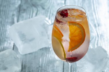 Portakal dilimli taze kokteyl ve gri ahşap masada buz.