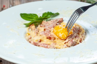 Yumurta sarısı, parmesan peyniri, pastırma ve fesleğenli makarna. İtalyan mutfağı..