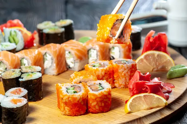 Yemek çubuğu kullanan ve havyarlı suşi tutan birinin kırpılmış görüntüsü.