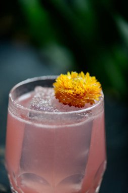 Çiçekle süslenmiş buzlu alkollü pembe kokteyl.