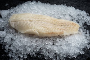 Ezilmiş buz üzerinde çiğ balık filetosu ahşap yüzeye uzanıyor.