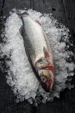 Ezilmiş buzun üzerindeki çiğ balık ahşap yüzeyde uzanıyordu.
